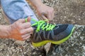 Male hands tying up shoelaces on a running sneaker, close up. Part of sportsman tying sneakers. Leg on a rock.