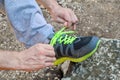 Male hands tying up shoelaces on a running sneaker, close up. Part of sportsman tying sneakers. Leg on a rock.