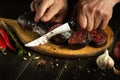 Male hands use a knife to cut blood sausage on a cutting board. Preparing a national dish on the kitchen table Royalty Free Stock Photo