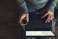 male hands using Laptop and coffee cup in hands sitting on a wooden floor