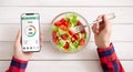 Male hands using smartphone and eating fresh salad Royalty Free Stock Photo