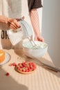 Male hands whipping whites cream in glass bowl with mixer on wooden table. Making sponge cake or red velvet cake Royalty Free Stock Photo