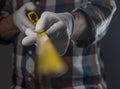 Male hands in white construction gloves holding yellow retractable tape measure tool forward to camera, close up