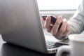 Male hands working on Laptop and holding a smart phone on the desk. Royalty Free Stock Photo