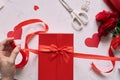 Male hands wrapping Valentine handmade present in paper with red
