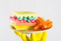 Male hands in yelliw gloves holding a burger made from sponges different colors. Concept of unhealthy food and non Royalty Free Stock Photo