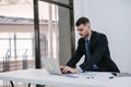 A male handsome caucasian using laptop working at office and checking toy cars on desk and car keys. Dealership and online sales Royalty Free Stock Photo