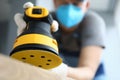 Male handy man hold yellow grinder with disc sander in hand closeup