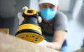 Male handy man hold yellow grinder with disc sander in hand closeup