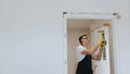 Male handyman carpenter at interior wood door installation with hammer and spirit level. Joiner assembling a doorpost or jamb