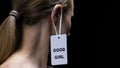 Male hanging good girl label on female ear, submission to man rules, disrespect