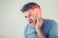 Male having ear pain touching his painful head on gray Royalty Free Stock Photo