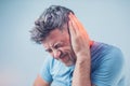 Male having ear pain touching his painful head on gray Royalty Free Stock Photo