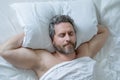 Male head on pillow. Gray hair man sleep in white bed. Senior man sleep in bed at bedroom. Mature man sleeps at home at Royalty Free Stock Photo