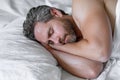 Male head on pillow. Gray hair man sleep in white bed. Senior man sleep in bed at bedroom. Mature man sleeps at home at Royalty Free Stock Photo