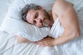 Male head on pillow. Gray hair man sleep in white bed. Senior man sleep in bed at bedroom. Mature man sleeps at home at Royalty Free Stock Photo