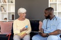 Male health worker with clipboard discussing with caucasian senior woman over medication dose