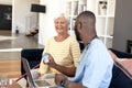 Male health worker with laptop discussing with caucasian senior woman over medication dose