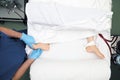 Male health worker palpates the feet of a dialysis patient in the bed