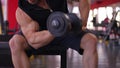 Male heavyweight athlete doing biceps exercises with dumbbells, workout in gym