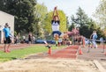 Male High school athlete at peak of long jump in track meet Royalty Free Stock Photo