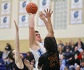 Male high school basketball player jumps for a shot, defended by two opposing players