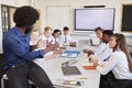 Male High School Teacher Sitting At Table With Teenage Pupils Wearing Uniform Teaching Lesson Royalty Free Stock Photo