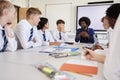 Male High School Teacher Sitting At Table With Teenage Pupils Wearing Uniform Teaching Lesson Royalty Free Stock Photo