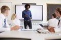 Male High School Teacher Standing Next To Interactive Whiteboard And Teaching Lesson To Pupils Wearing Uniform Royalty Free Stock Photo