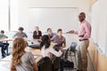 Male High School Tutor Standing At Whiteboard Teaching Class