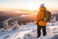 Male hiker admiring a scenic view from a snowy mountain top. Adventurous young man with a backpack. Hiking and trekking on a