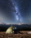 Male hiker have a rest in his camping in the mountains at night under beautiful night sky full of stars and milky way Royalty Free Stock Photo
