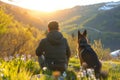 Male hiker and his pet dog admiring a scenic view in flowering meadow at spring. Adventurous young man with his dog friend. Hiking