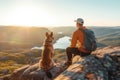 Male hiker and his pet dog admiring a scenic view from a mountain top. Adventurous young man with a backpack. Hiking and trekking Royalty Free Stock Photo