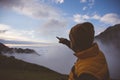 Male hiker on a mountain pointing the cloudscape