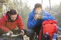 Male hiker reading map while friend having coffee in forest Royalty Free Stock Photo