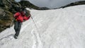 Hiker descending a late spring snow field on his way down from a scenic mountain peak in the Swiss Alps