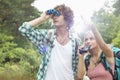 Male hiker using binoculars while woman showing him something in forest