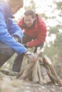 Male hikers lighting bonfire in forest