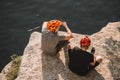 male hikers in protective helmets resting and eating canned food on rocky cliff