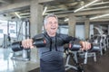 Male in his 60s enjoys dumbell workout in the fitness center