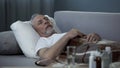 Male in his 60s sleeping in bed at home, pills and fluids standing on the table