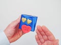 Male holding blue gift box with two golden hearts and a red heart shaped sticker with sign love you and pointing with other hand. Royalty Free Stock Photo