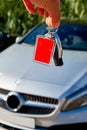 Male holding car keys with car on background. Royalty Free Stock Photo