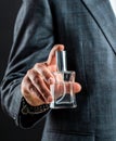 Male holding up bottle perfume. Hand in with wrist watch in a business suit. Perfume or cologne bottle and perfumery