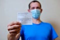 male is holding a vaccination record card and corona virus vaccine vials. Passport of immunity to the coronavirus in the hands of