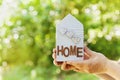 Male holds in hands house decorated hearts on green bokeh background. Real estate, buying a new home, insurance, sun energy, eco.