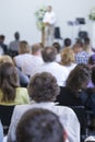 Male Host Speaking on Stage in Front of Group of Professionals During a Conference.