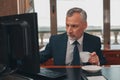 Male hotelier works at a computer and drink coffee while sitting in his office in a hotel Royalty Free Stock Photo