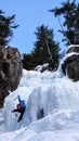 Male ice climber in a blue jacket on a gorgeous frozen waterfall climbing in the Alps in deep winter Royalty Free Stock Photo